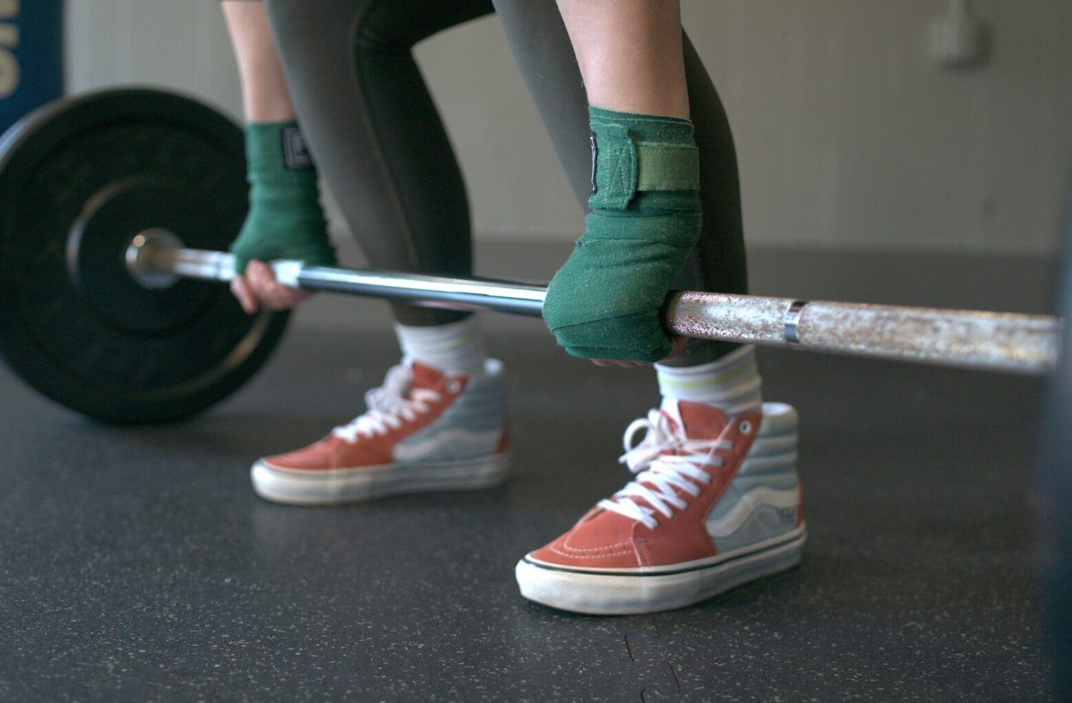 Gloved hands deadlifting barbell at Strong Martha